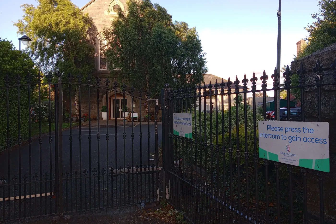 Entrance gates of St Pappin's Nursing Home, Dublin, with intercom notice and the converted church building behind