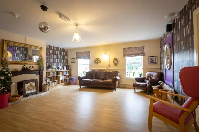 Beechwood Nursing Home, Leighlinbridge, Co. Carlow: interior sitting room with leather sofa, fireplace and bookcase wallpaper, no people
