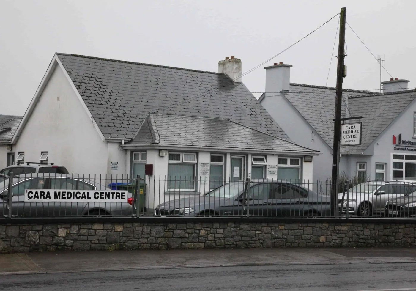 Cara Medical Centre, Newcastle West, Co. Limerick: Front of the single-storey practice building from the road, with the Cara Medical Centre sign on the railing and the hanging sign showing (069) 77040; parked cars, no people