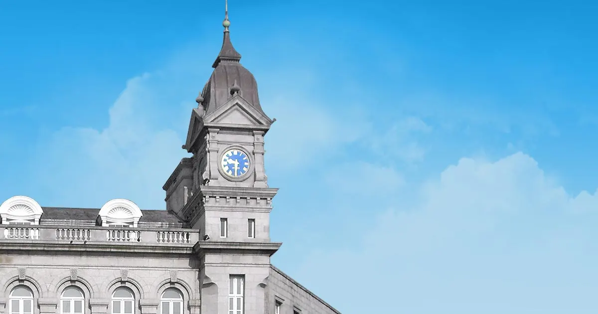 Mercer's Medical Centre, Dublin, Co. Dublin: Granite clock tower and upper facade of the old Mercer's Hospital building composited against a graphic blue sky.