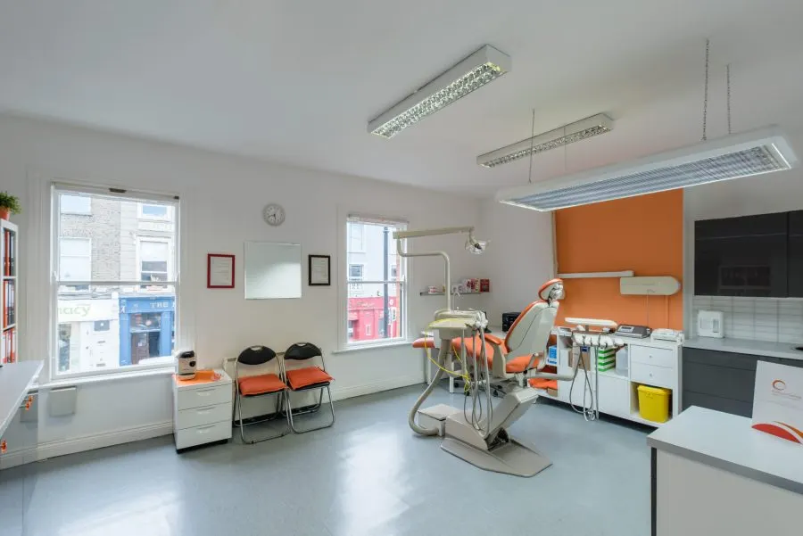 Rathgar Dental Practice, Dublin, Co. Dublin: Rathgar Dental Practice treatment room with orange dental chair, waiting chairs and windows onto the shops on Rathgar street.