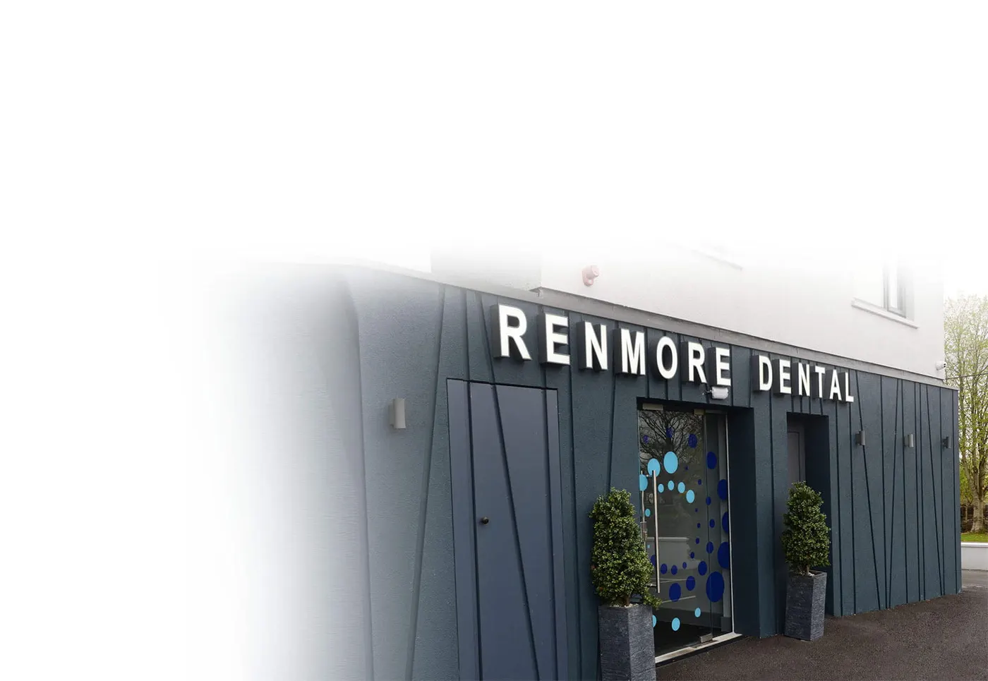 Renmore Dental, Galway, Co. Galway: Exterior of Renmore Dental with dark cladding, 'Renmore Dental' lettering, dotted glass entrance door and two potted shrubs; the left side fades to white.